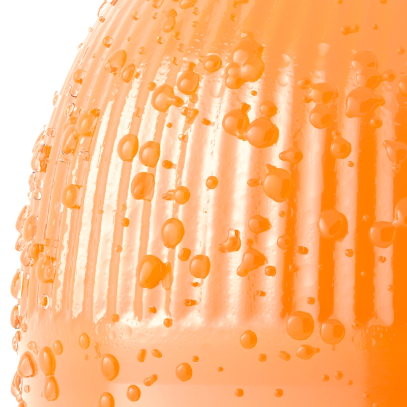 A close-up of an orange drink bottle with condensation and water droplets.