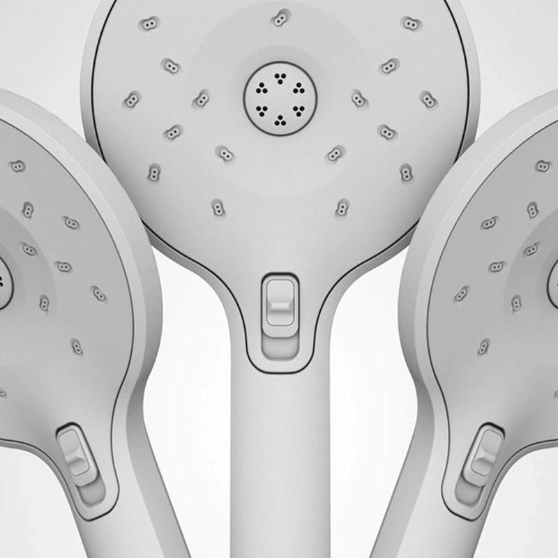 Closeup of three 'clay render' shower heads with buttons on a grey background.