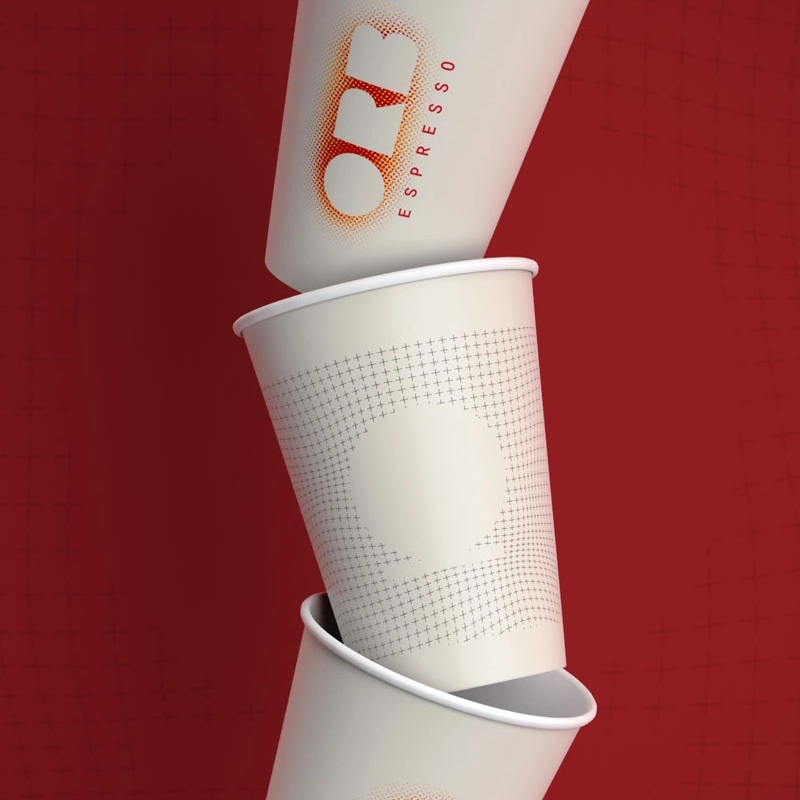 Closeup of three tske-away coffee cups with the ORB Espresso logo, stacked on top of each other against a red background.