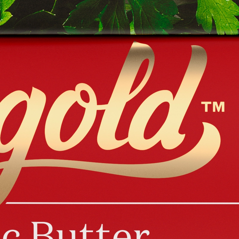 A close-up of the word "Gold" in gold lettering on a red background, with parsley leaves visible in the background.